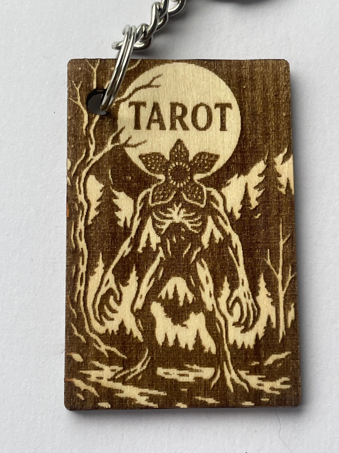Wooden tarot card with floral design and 'Tarot' engraving on a white background