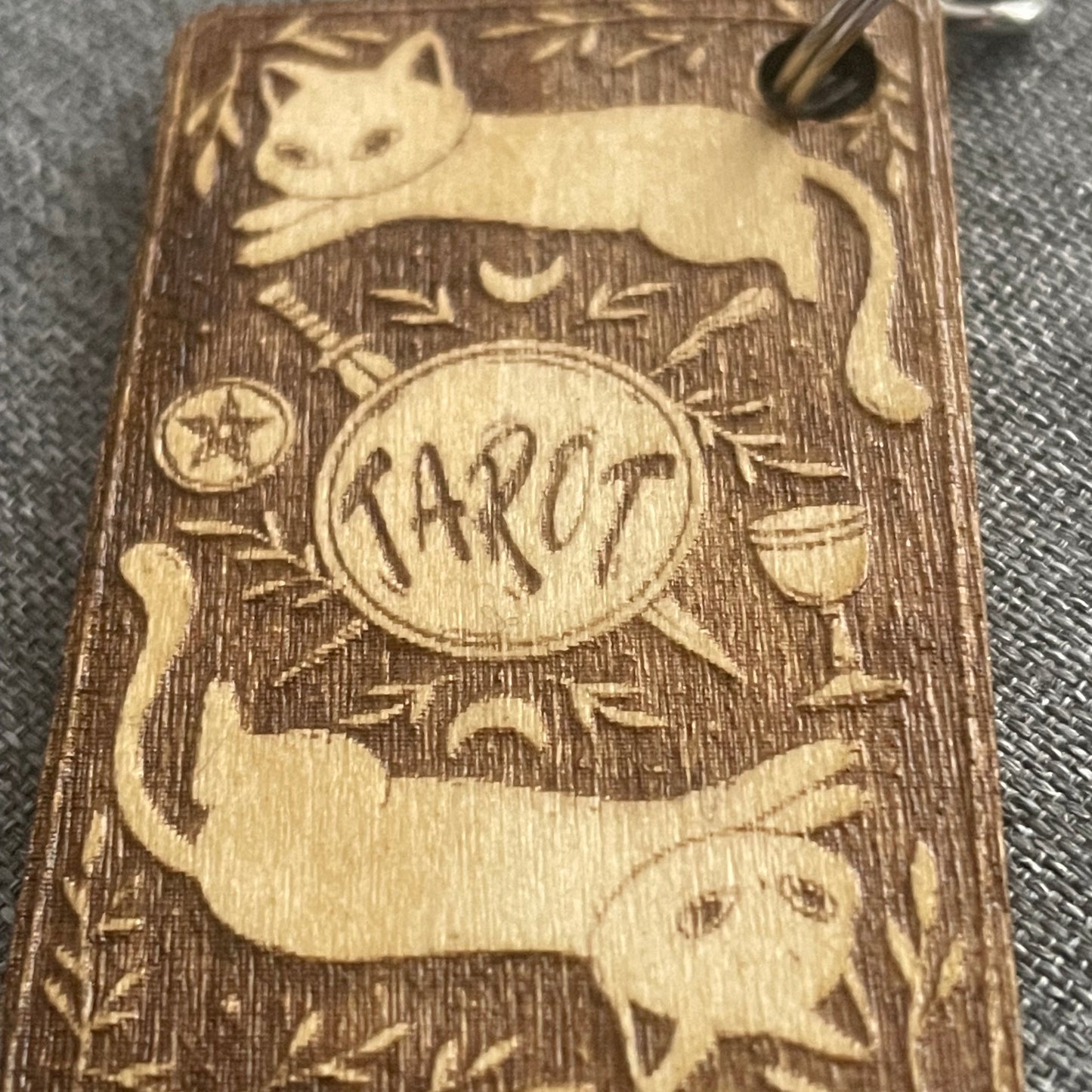 Wooden keychain with engraved design of a cat, moon, and star on a textured surface