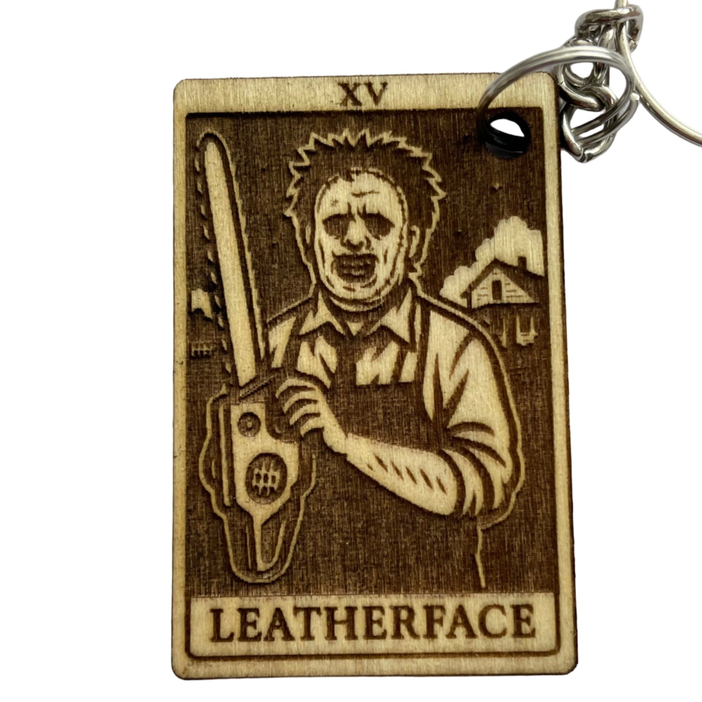 Keychain with a design of a person holding a chainsaw and the word 'LEATHERFACE' on a white background