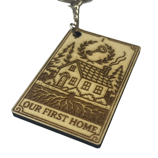 Keychain with house illustration and 'Our First Home' text on a white background