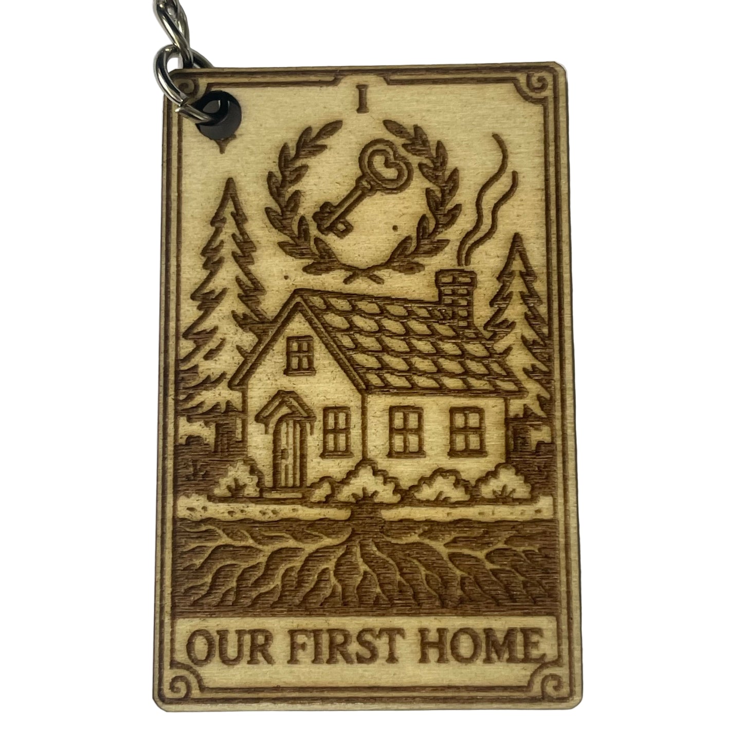Wooden keychain with engraved house and trees design on a white background