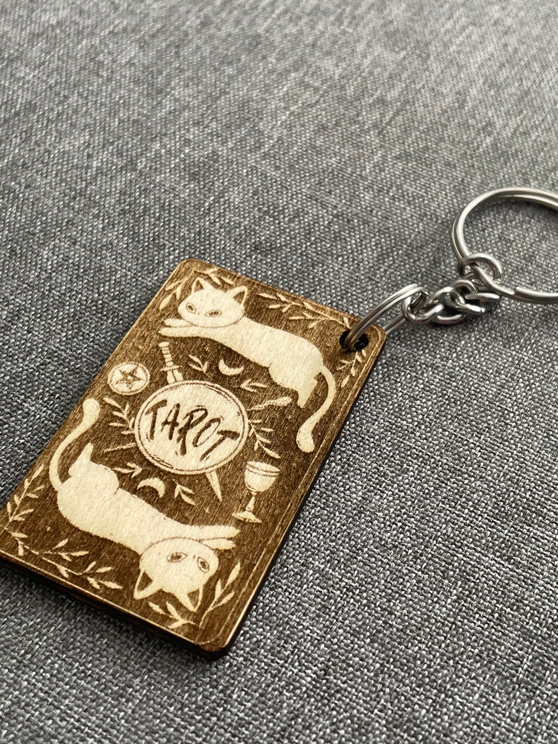 Keychain with engraved design of cats and a moon on a textured gray background
