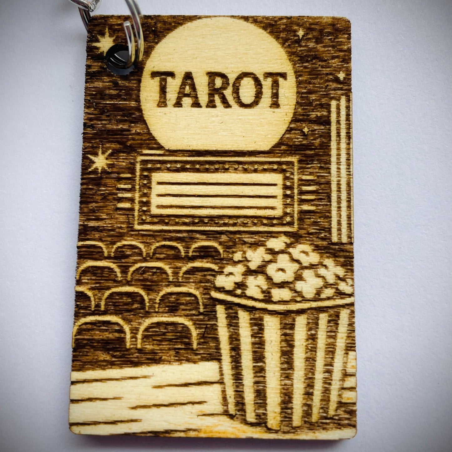 Wooden tarot card keychain with engraved design on a gray background