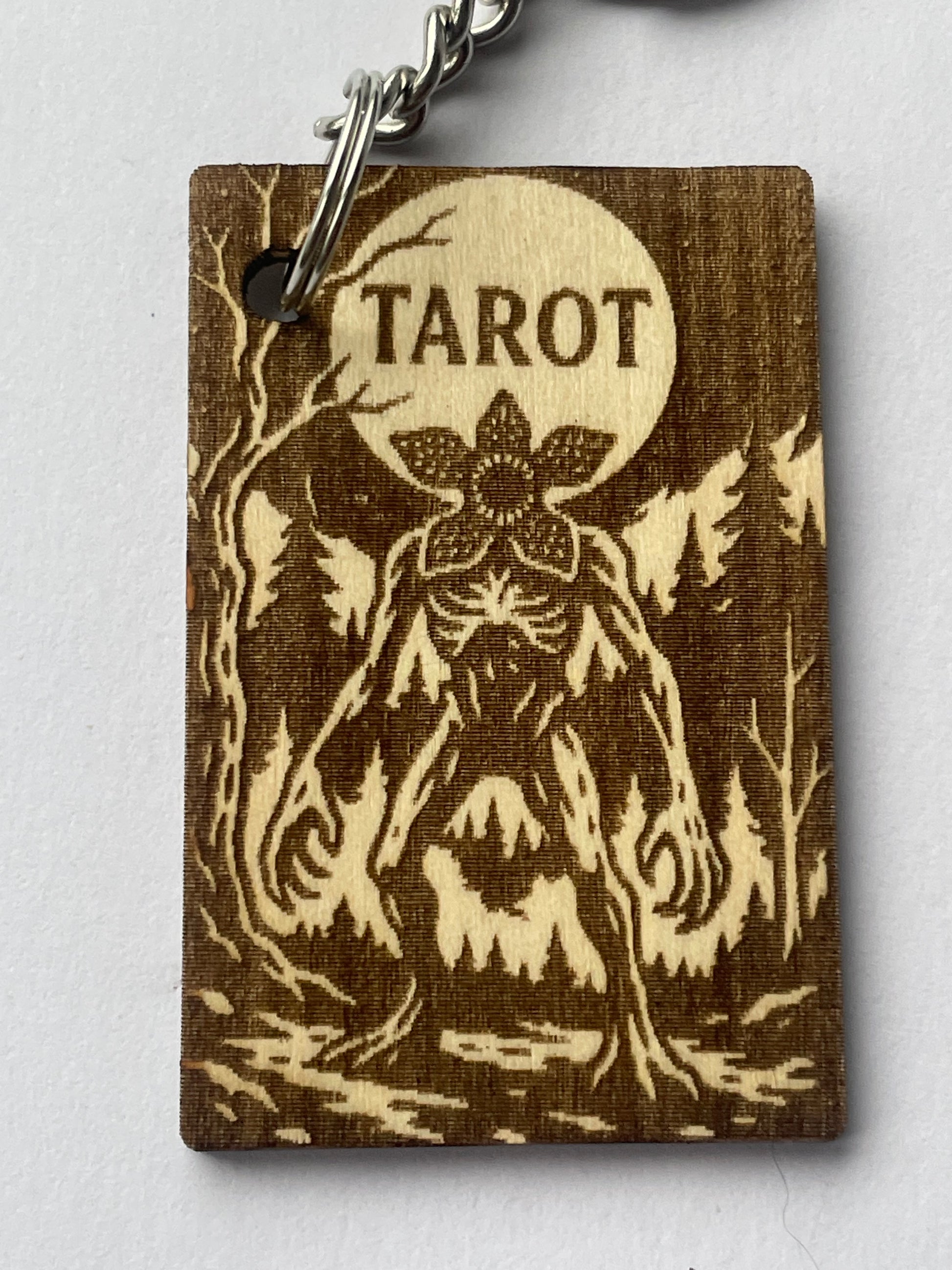 Wooden tarot card with floral design and 'Tarot' engraving on a white background