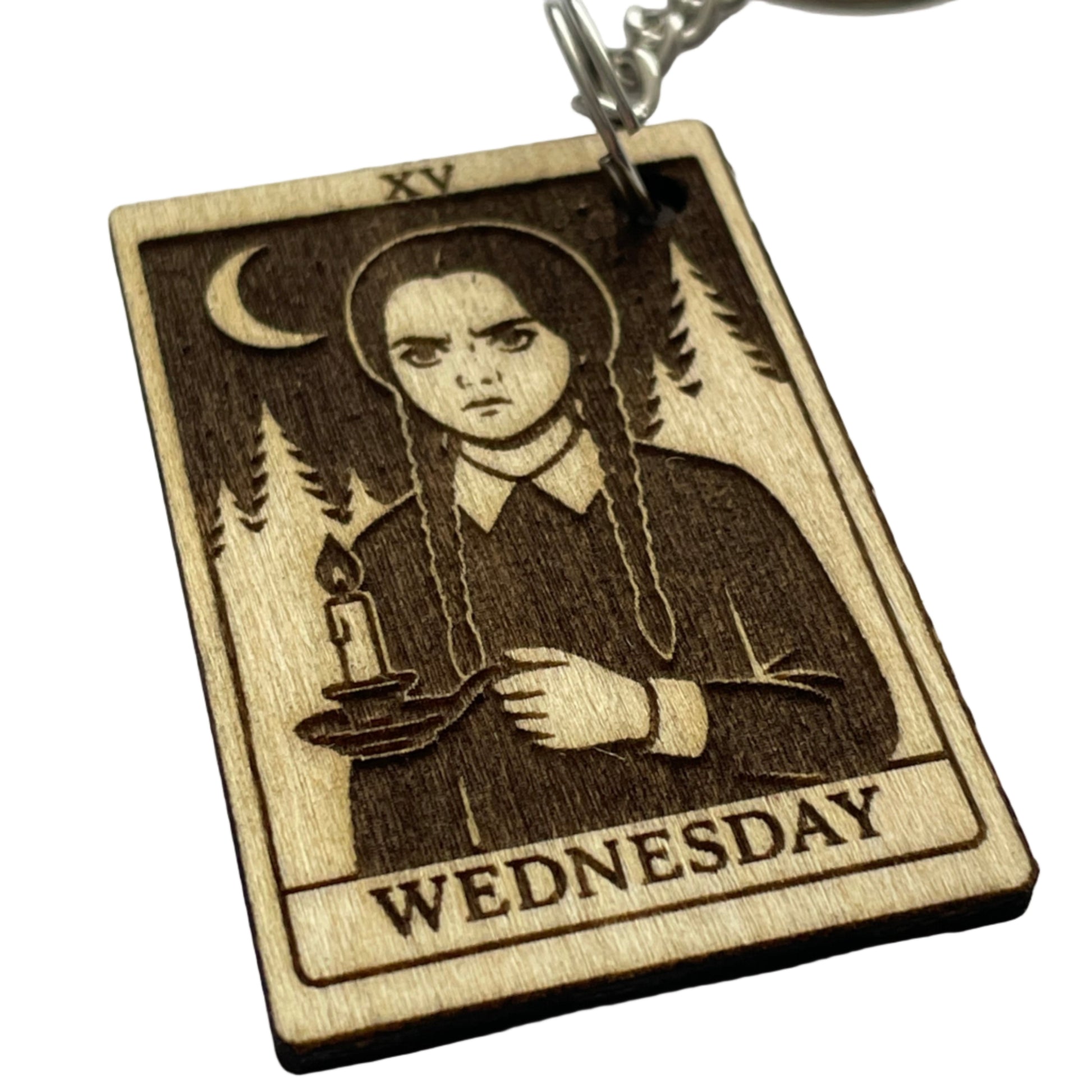 Wooden keychain with a design of a person holding a gun, labeled 'Wednesday', on a light gray background.