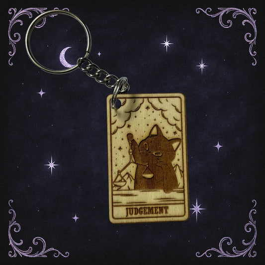 Keychain with a tarot card design featuring a cat and the word 'Judgement' on a dark background with stars.