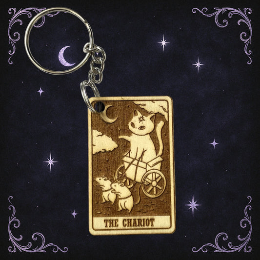 Keychain with 'The Chariot' tarot card design on a dark background with stars and moon.