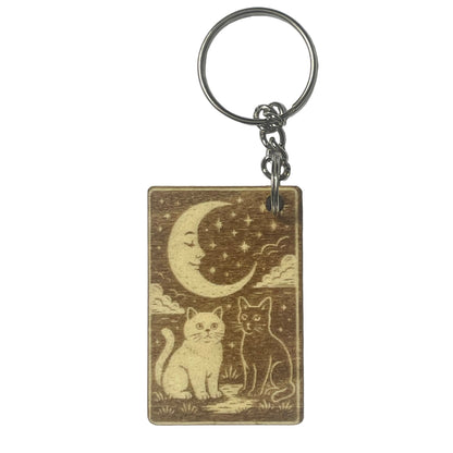 Keychain with two cats under a moon and stars design on a plain background