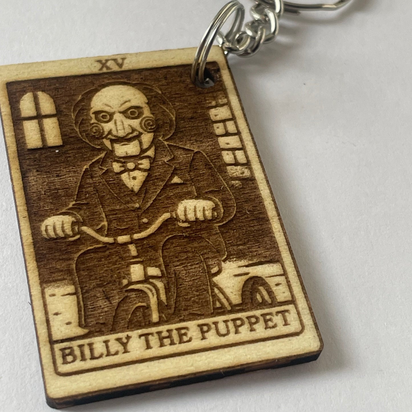 Wooden keychain with engraved design of a character labeled 'Billy the Puppet' on a white background