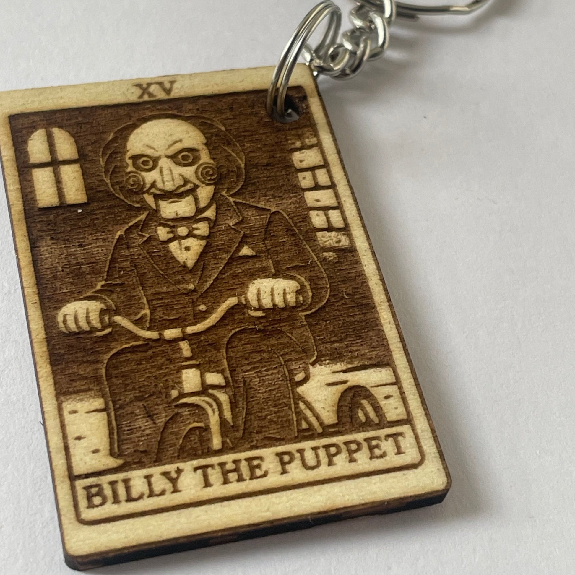 Wooden keychain with engraved design of a character labeled 'Billy the Puppet' on a white background