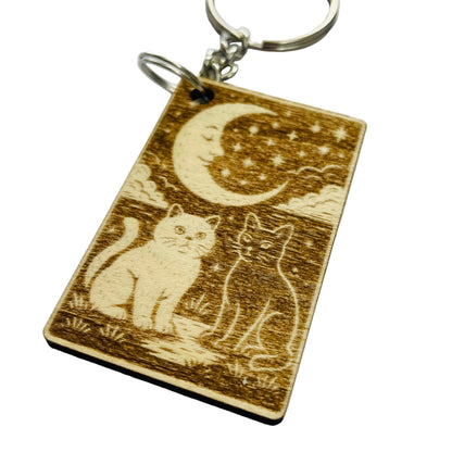 Wooden keychain with engraved design of two cats and a moon on a white background