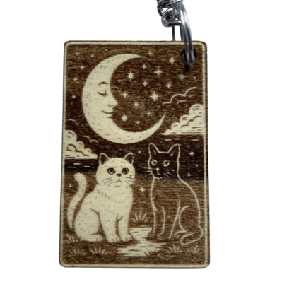 Wooden keychain with two cats and a moon design on a light blue background