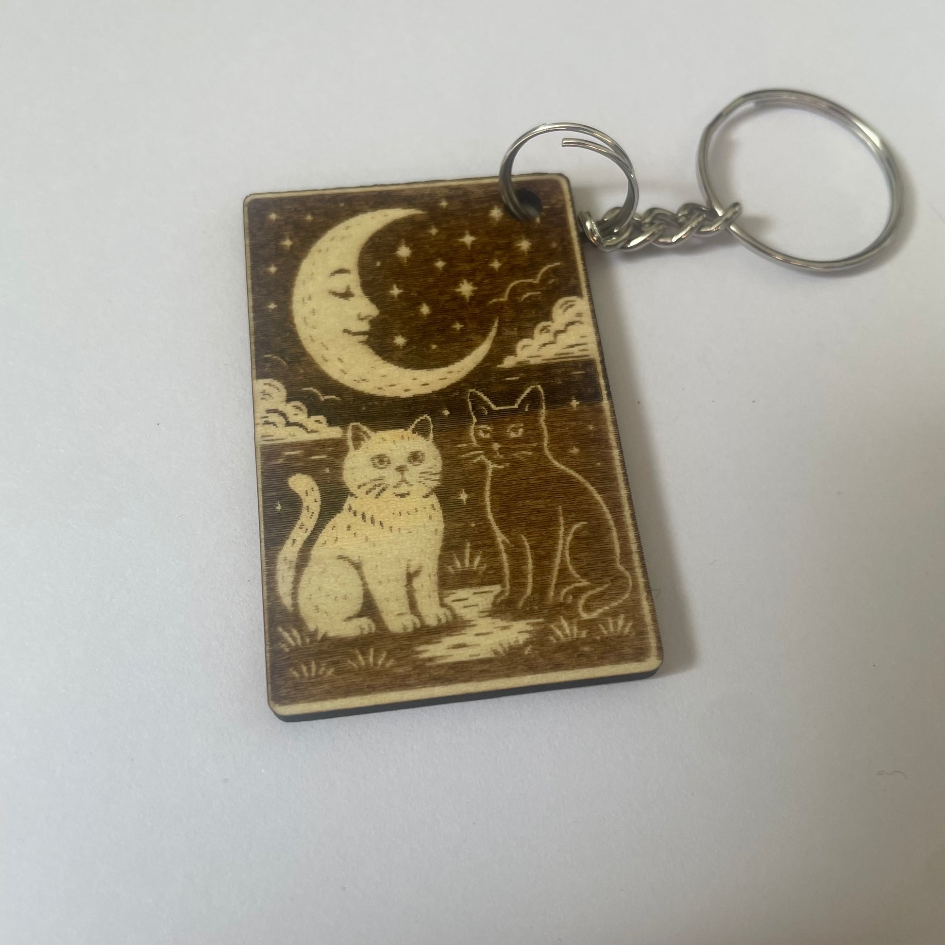 Keychain with two cats under a moon and stars design on a white background