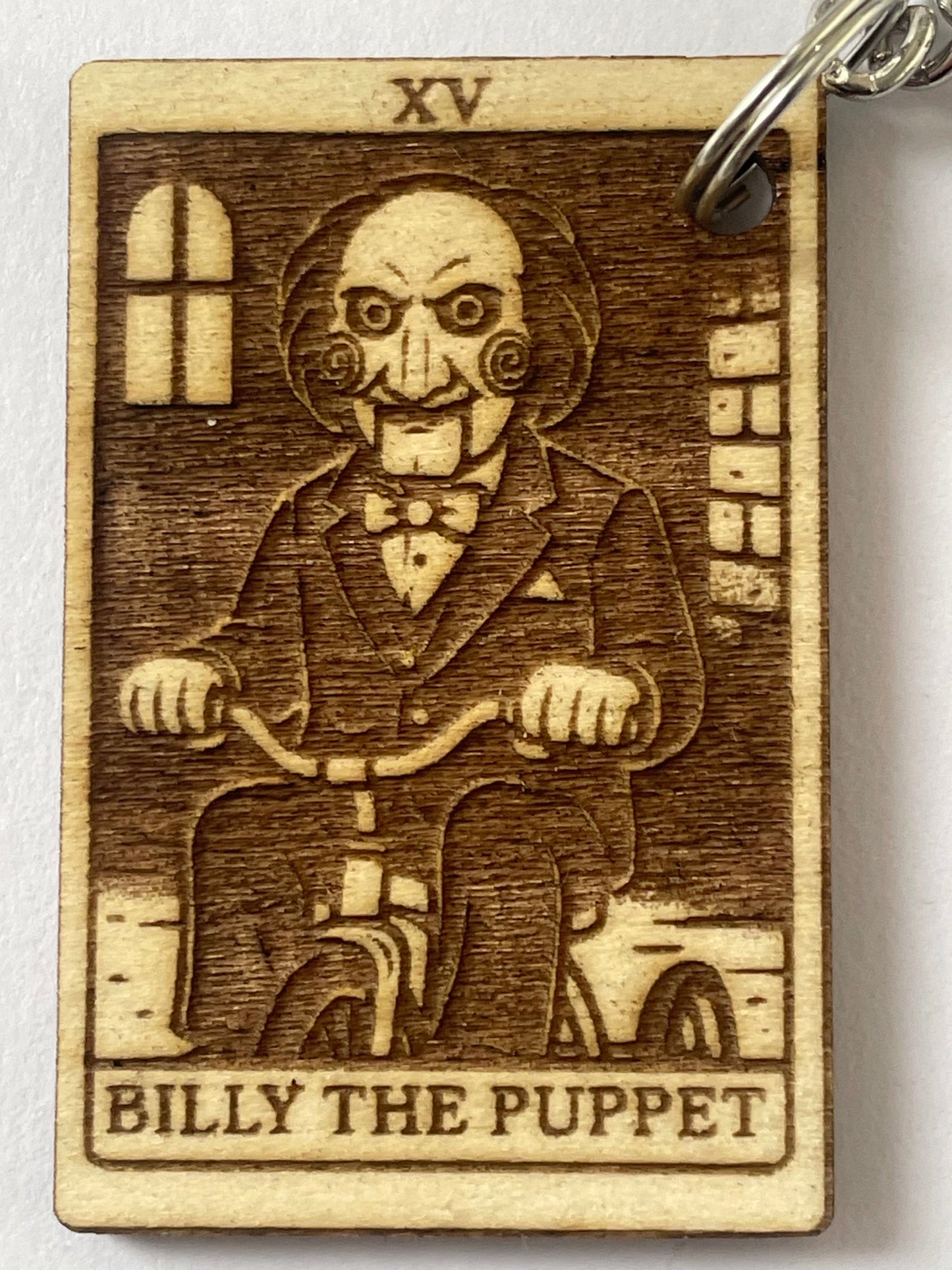 Wooden keychain with engraved illustration of a character labeled 'Billy the Puppet' on a white background.