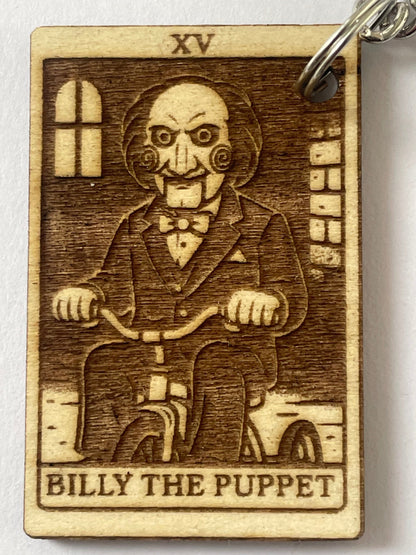 Wooden keychain with engraved illustration of a character labeled 'Billy the Puppet' on a white background.