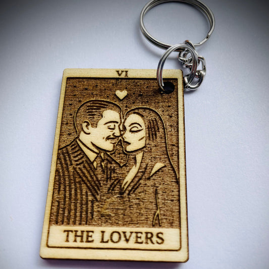 Wooden keychain with engraved illustration of 'The Lovers' tarot card on a gray background
